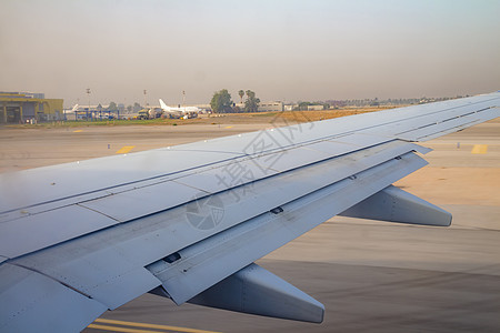 日出时班古里昂机场跑道上的飞机机翼航空飞机场太阳航空公司旅行航班地面车辆沥青土地图片