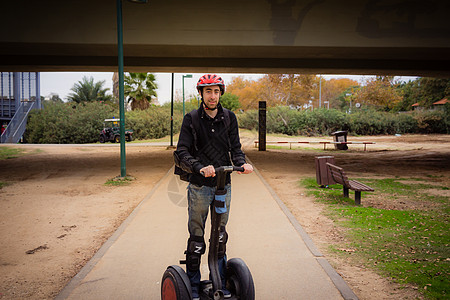 男人在公园的Segway上骑马路面娱乐乐趣男性女性车辆旅游城市吸引力运输图片