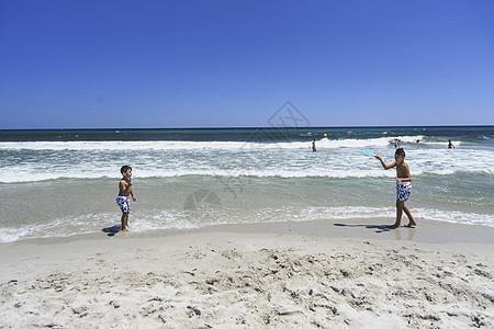 男孩在海滩打网球朋友们闲暇玩具网球女性游戏青少年姐姐天空蓝色图片