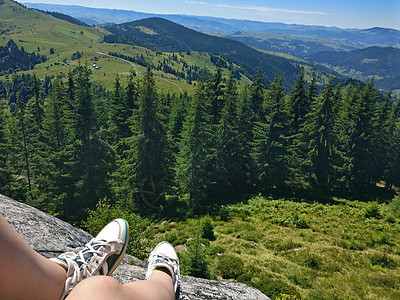 旅行中坐在高山顶上的旅行者腿脚顶峰活动自由天空潮人山脉女士闲暇远足成人图片