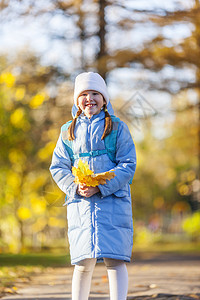 女孩持山树叶快乐女性女学生乐趣童年蓝色叶子季节公园橙子图片