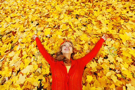 女人躺在秋叶上喜悦幸福享受公园女性金子红色森林乐趣叶子图片