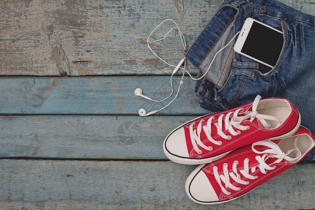 红复古运动鞋和智能手机及耳耳机牛仔布配饰衣服音乐桌子短裤旅行电话蓝色口袋图片