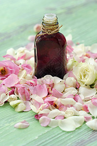 用于斯帕治疗的玫瑰基本油和花瓣木头白色粉色玻璃花朵温泉美容红色绿色背景图片