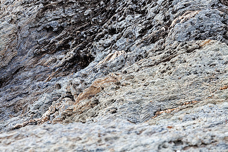 海滩上锋利的灰色岩石矿物悬崖海洋海景材料旅行石头支撑海浪天空图片