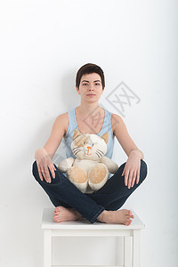年轻迷人的微笑女性练习瑜伽 坐在半莲花练习姿势 穿着深蓝色牛仔裤室内全长 白色毛绒玩具猫在她的腿上锻炼生活运动压力教练训练小猫辅图片