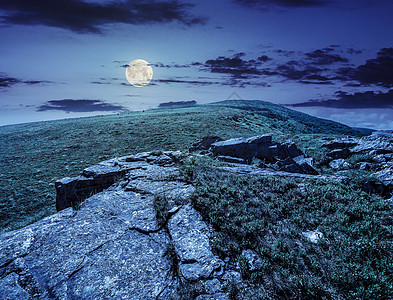 夜晚在山顶的石头上草地爬坡月亮晴天岩石旅行天空远足地面国家图片