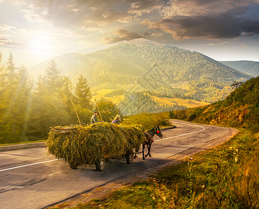 日落时乘着马车干草前往山上图片