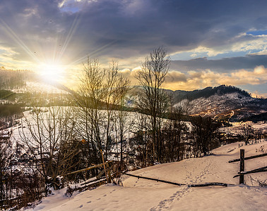 冬季日落时山附近的雪地农村地区围栏上的栅栏图片