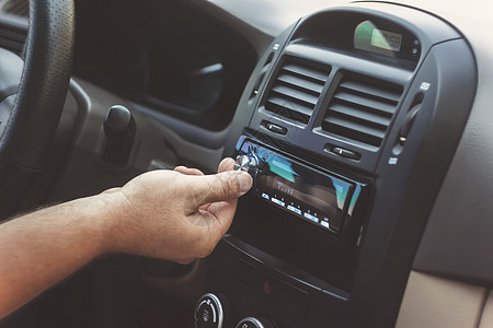 男人的手扭动音量 在回溯汽车空气按钮调频力量控制音乐播放器手指车辆护发素立体声图片