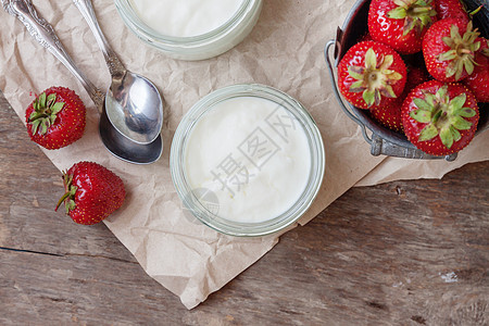 酸奶和草莓放在玻璃杯中 水桶加新鲜的蒸汽缸羊皮纸勺子奶油早餐玻璃食物浆果水果甜点奶制品图片