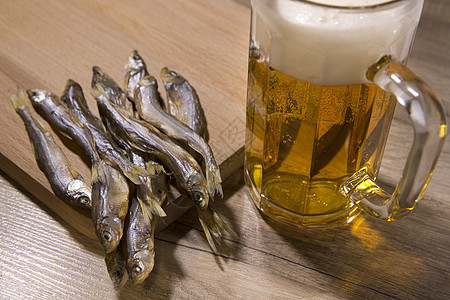 啤酒和木桌上的干鱼木头酒吧美食腌鱼盐渍食物泡沫状酒精玻璃蟑螂图片