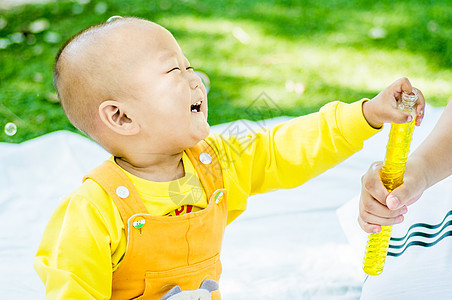 一个婴儿在公园的垫子上玩耍男生父母场地家庭玩具衣服乐趣孩子院子花园图片