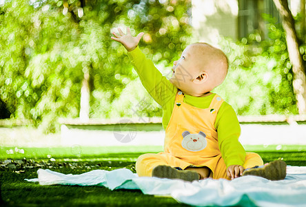 一个婴儿在公园的垫子上玩耍男生乐趣玩具草地场地衣服家庭父母孩子儿子图片
