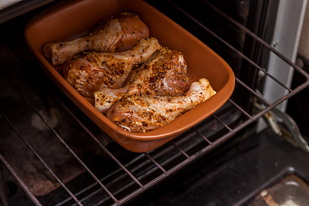 生鸡腿在烤箱里 反转到烤箱烘烤古董制品脆皮调色菜单烧烤香料宏观盘子图片