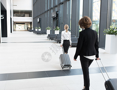 商业人士在机场行走建筑套装女士商务旅游团体滚动成人运动手提箱图片