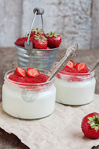 酸奶加果酱酱 在玻璃和一桶新鲜草莓甜点牛奶羊皮纸奶油水果饮食勺子早餐奶制品浆果图片