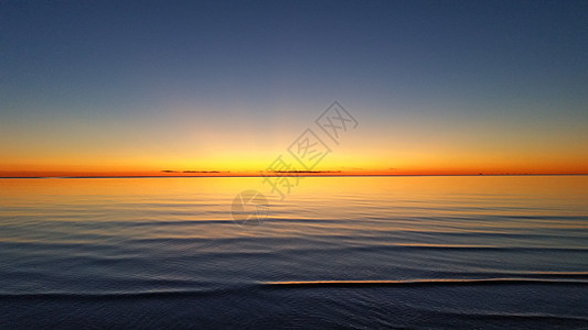 宁静的海水上美丽的橙色夕阳晴天日落海岸反射旅行太阳海洋天际天空假期图片