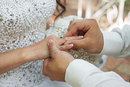 新郎把戒指放在新娘的手上 照片特写珠宝金子手指推杆花束女士裙子男人女性花朵图片