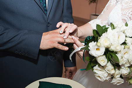 结婚戒指和新娘和新郎的手 新婚夫妇在仪式上 婚姻 恋爱中的男人和女人 两个快乐的人庆祝成为一家人金子交换花朵玫瑰家庭接待女士花束图片