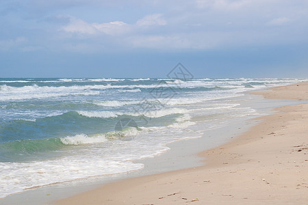 海滨海浪在沙沙滩上滚动 暴云日出图片