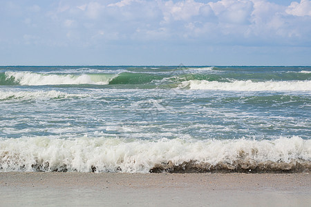海滨海浪在空沙滩上滚动 暴云日出图片