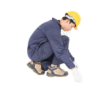 年轻工人在单人区 用白色隔离的胶带措施头盔磁带卷尺石匠男人测量地面建造建筑工人图片