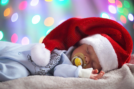 戴圣塔帽子的新生婴儿毯子背景男生休息童年魔法毛巾新年说谎辉光图片