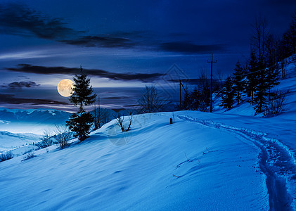 夜间穿过雪山坡的农村人行道图片