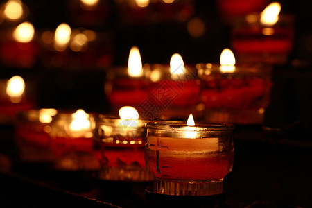 在黑暗教堂燃烧的红蜡烛特写火焰红色玻璃烛光祷告宗教仪式崇拜团体寺庙图片