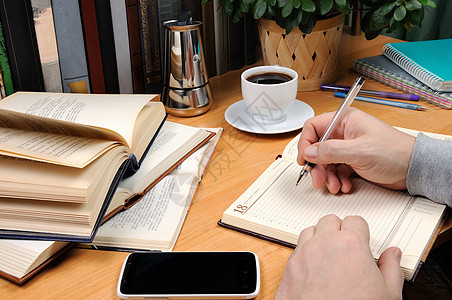 男人在笔记本上作笔记桌子全书百科遗产杯子咖啡壶知识训练咖啡教程图片