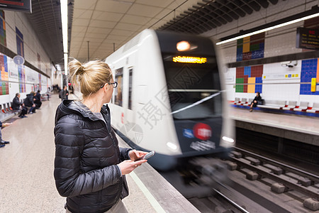 有个女人的手机在等地铁女士旅行航程假期乘客游客电话过境火车车皮图片