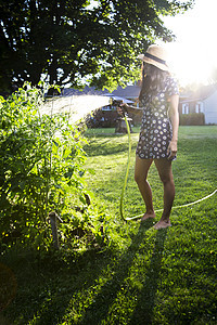 青年妇女浇水花园园丁园艺工作女孩生长爱好闲暇植物群植物微笑图片
