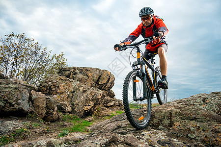红色骑车自行车的赛车员 在秋天落岩轨上 极端运动和概念骑士运动员活动踪迹娱乐车轮头盔耐力赛男人速度图片