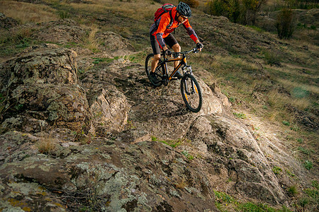 红色骑车自行车的赛车员 在秋天落岩轨上 极端运动和概念下坡男人天空乐趣运动员岩石冒险速度爬坡骑士图片