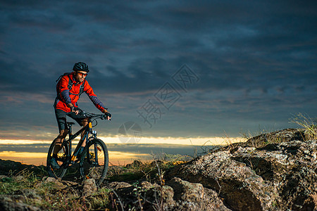 红色骑自行车的骑自行车者在秋天岩石足迹在日落 极限运动和耐力赛自行车概念骑士成人山地车头盔下坡冒险太阳运动员活动爬坡图片