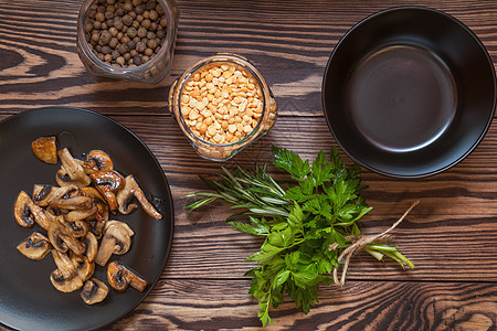 黑盘炒蘑菇盘子奶油油炸迷迭香蔬菜白色桌子勺子面包食物图片