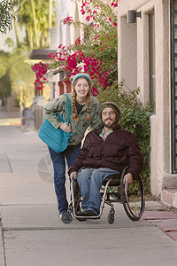 人行道上轮椅上的青年男女姿势胡须男性夹克夫妻街道男人女朋友城市潮人图片