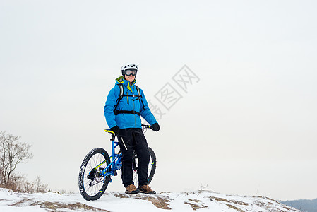 蓝色休息中的赛车手的肖像 在落基温冬山上用山堤打劫 极端运动和概念运动员娱乐速度岩石头盔天空锻炼活动踪迹自行车图片