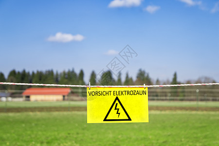 绿色草地上的电网围栏房子黄色力量栅栏暗示语言警告危险蓝色森林图片