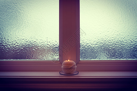 冬季黄昏时燃烧蜡烛和冰霜的窗户图片