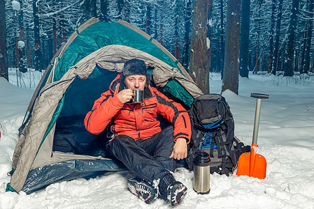 一位在冬季森林中失落的游客 坐着喝茶图片