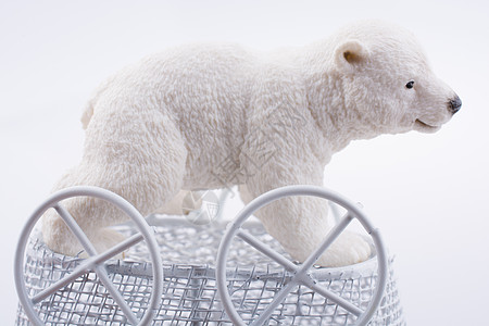 小北极熊在玩具婴儿车中的比值天空白色黑色摇篮孩子婴儿野生动物爪子气候车轮图片