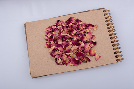 螺旋笔记本上的干玫瑰花瓣笔记味道温泉草本植物字帖床单教育记事本治愈商业图片