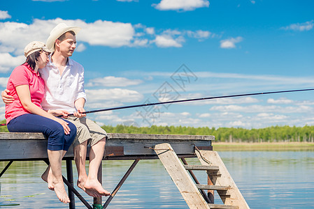 在美丽的湖边钓鱼的码头上 年轻快乐的情侣图片