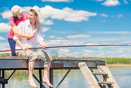 男人用钓鱼杆和他心爱的女人 在木头码头上图片