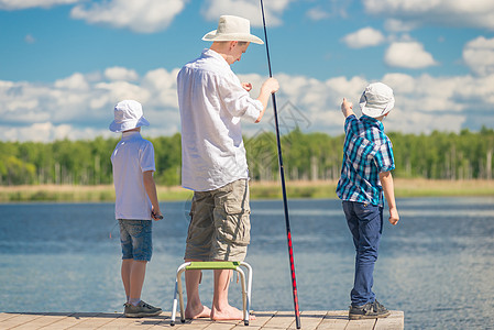 男孩和父亲在湖边一个美丽的地方钓鱼图片
