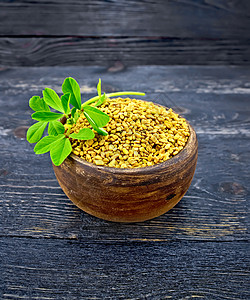 Fenugreek 木板上粘土碗中的叶叶图片