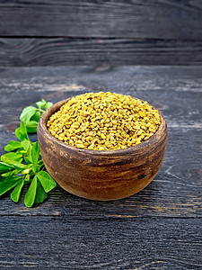 Fenugreek 在黑木板上用粘土碗叶图片