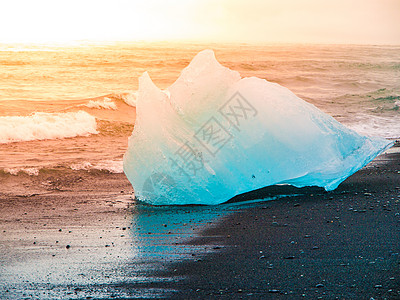 冰岛Jokulsarlon冰川湖附近日出时黑沙滩的海浪使冰山崩裂水晶波浪天空戏剧性太阳火山蓝色气候花饰海洋图片